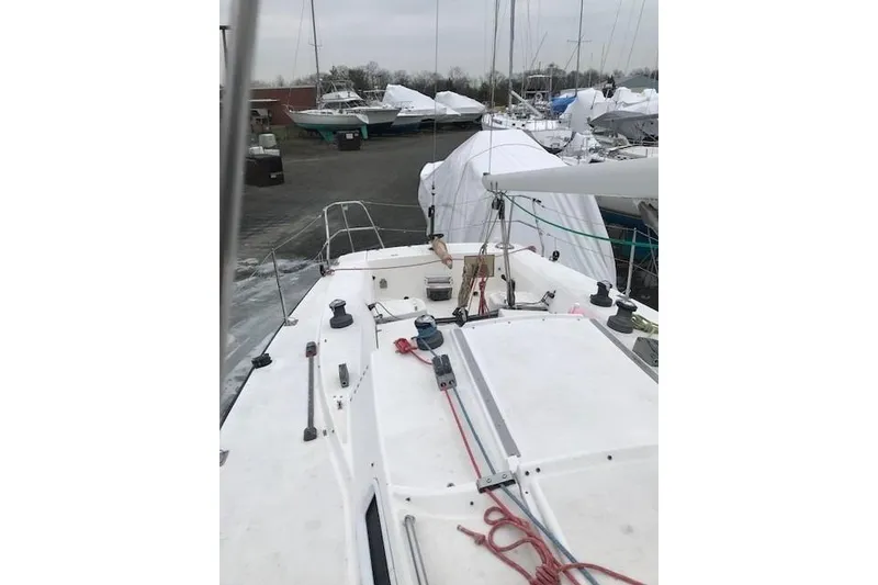 Slide: The Image of 1997 JBoat J 105 sailboat on land, surrounded by covered boats. - 15