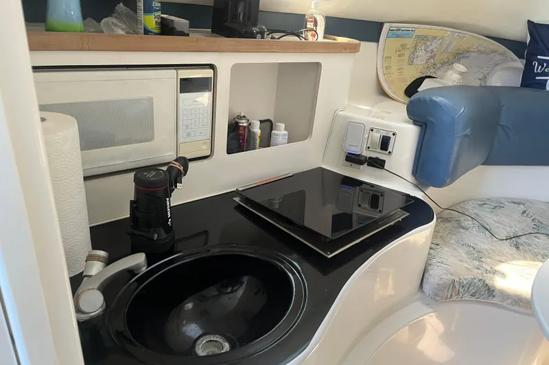 Slide: The Image of Compact kitchen area in a 2002 Century 3200 Walk-Around boat with sink and microwave. - 22