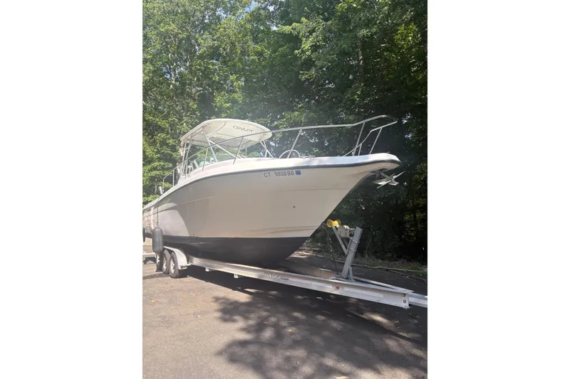 The Image of 2004 Century 3200 WA boat on trailer, parked outdoors with trees in background. - 0
