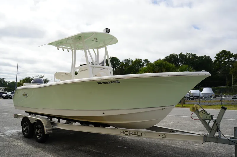Slide: The Image of 2022 Sea Hunt Ultra 229 boat on a Robalo trailer, parked outdoors. - 2