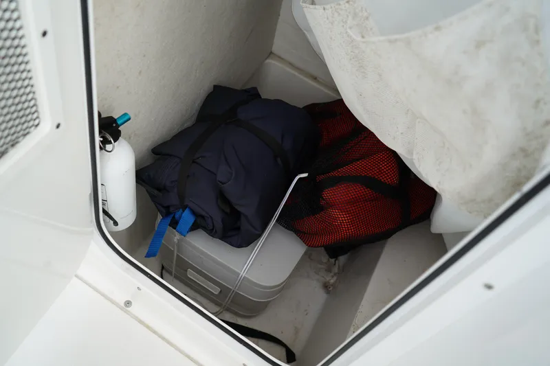 Slide: The Image of Storage compartment in 2022 Sea Hunt Ultra 229 boat with gear and fire extinguisher. - 21
