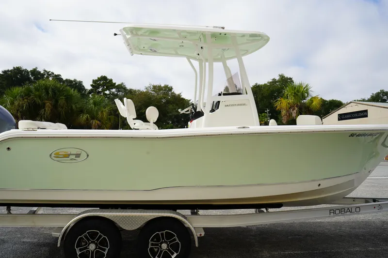 Slide: The Image of 2022 Sea Hunt Ultra 229 boat on trailer, side view with palm trees in background. - 3