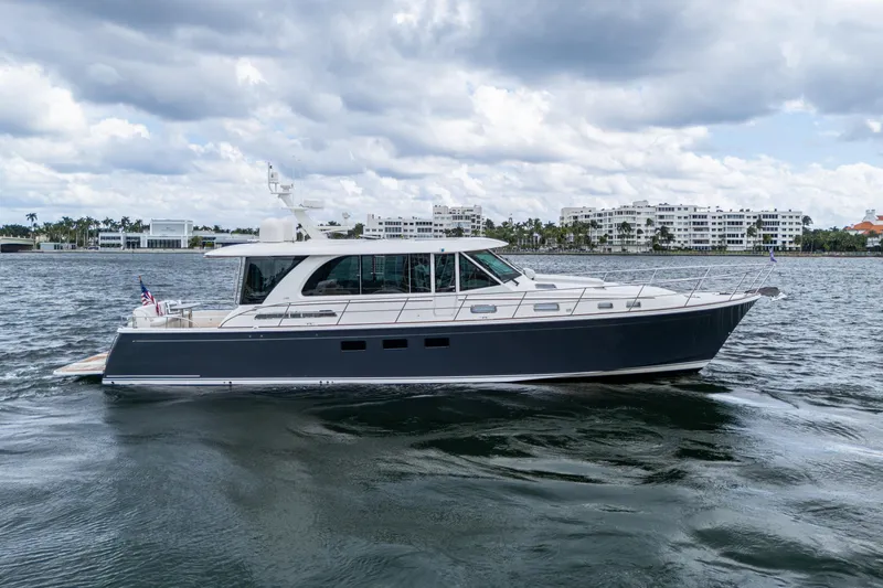 Slide: The Image of 2022 Sabre 58 Salon Express yacht cruising on a calm waterway under cloudy skies. - 0