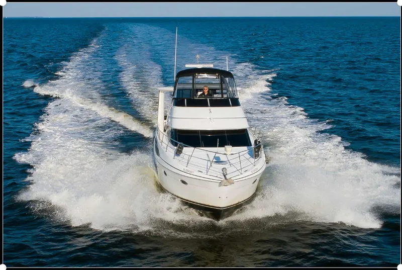 Slide: The Image of 2003 Carver 444 Cockpit Motor Yacht cruising on open water, leaving a wake behind. - 2