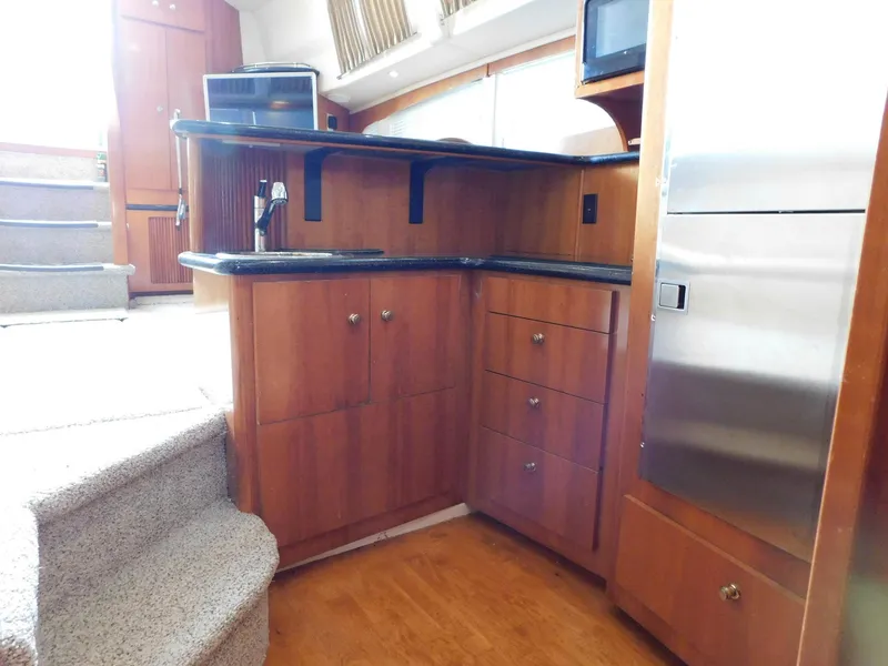 Slide: The Image of 2003 Carver 444 Cockpit Motor Yacht interior with wooden cabinetry and stainless steel appliances. - 31