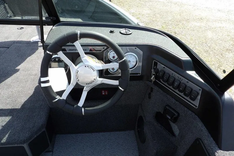 Slide: The Image of 2026 Lund 1875 Impact XS Sport boat dashboard with steering wheel and control panel. - 27