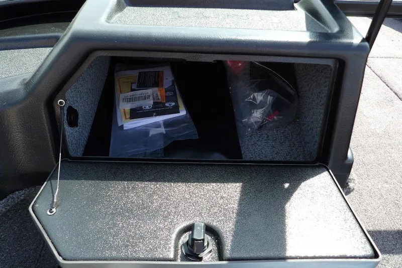 Slide: The Image of Storage compartment of 2026 Lund 1875 Impact XS Sport boat, containing manuals and plastic bags. - 32