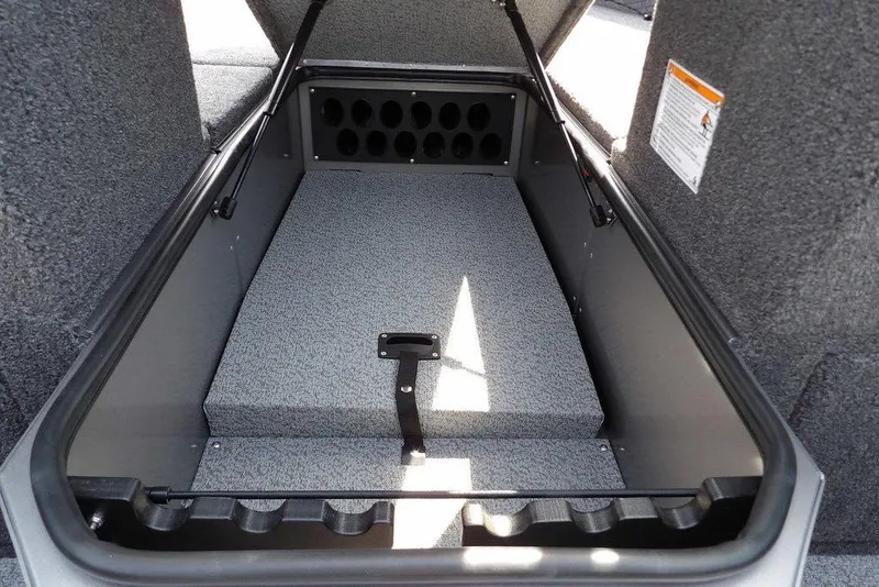 Slide: The Image of 2026 Lund 1875 Impact XS Sport boat storage compartment with rod holders and carpeted interior. - 40