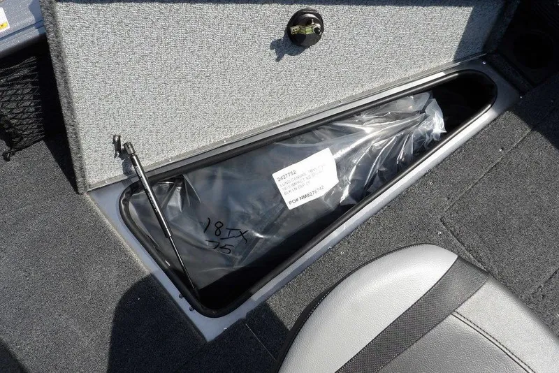 Slide: The Image of Storage compartment in 2026 Lund 1875 Impact XS Sport boat, featuring secure latch and carpeted interior. - 42