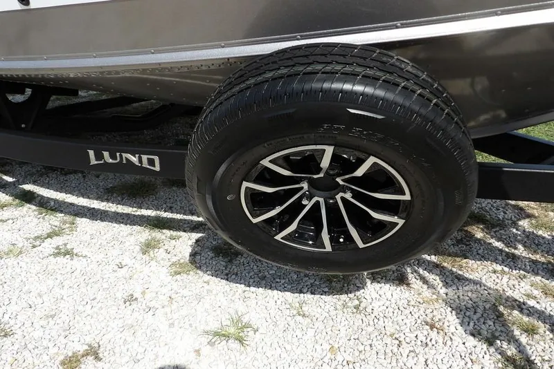 Slide: The Image of 2026 Lund 1875 Impact XS Sport trailer wheel on gravel surface. - 43