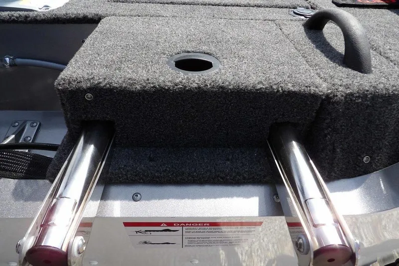 Slide: The Image of 2026 Lund 1875 Impact XS Sport boat interior with carpeted storage and metal supports. - 52