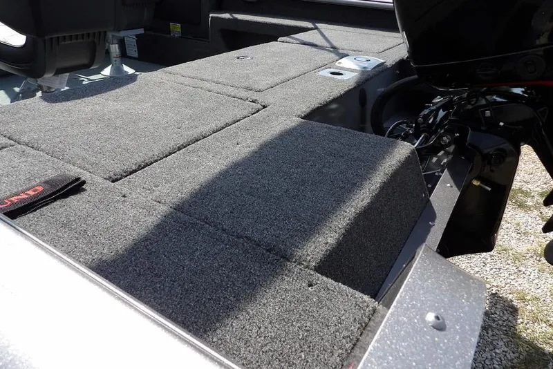 Slide: The Image of 2026 Lund 1875 Impact XS Sport boat interior with carpeted deck and motor. - 9