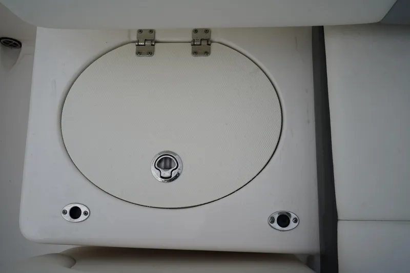 Slide: The Image of 2023 Robalo R222 Explorer boat storage compartment with circular hatch and metal latch. - 10