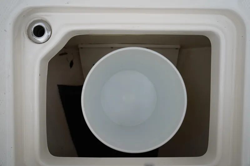 Slide: The Image of 2023 Robalo R222 Explorer boat compartment with a white bucket inside. - 27