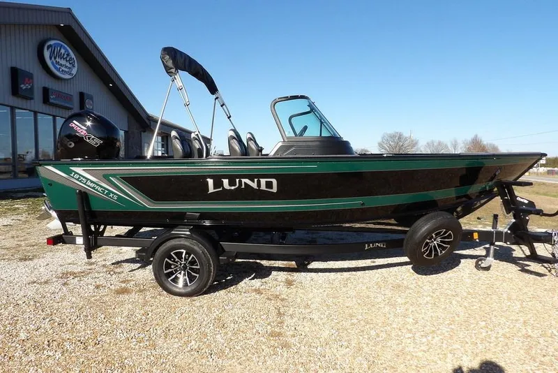The Image of 2026 Lund 1875 Impact XS Sport boat on trailer, parked outdoors. - 1