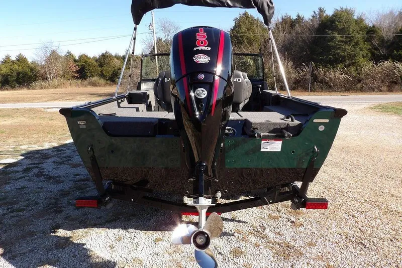 Slide: The Image of 2026 Lund 1875 Impact XS Sport boat with powerful outboard motor, parked on gravel. - 10