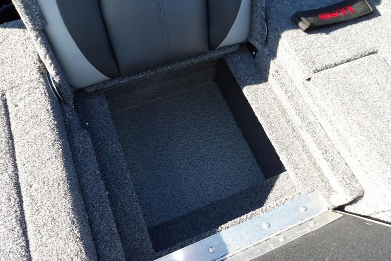 Slide: The Image of 2026 Lund 1875 Impact XS Sport boat storage compartment with gray carpet interior. - 13