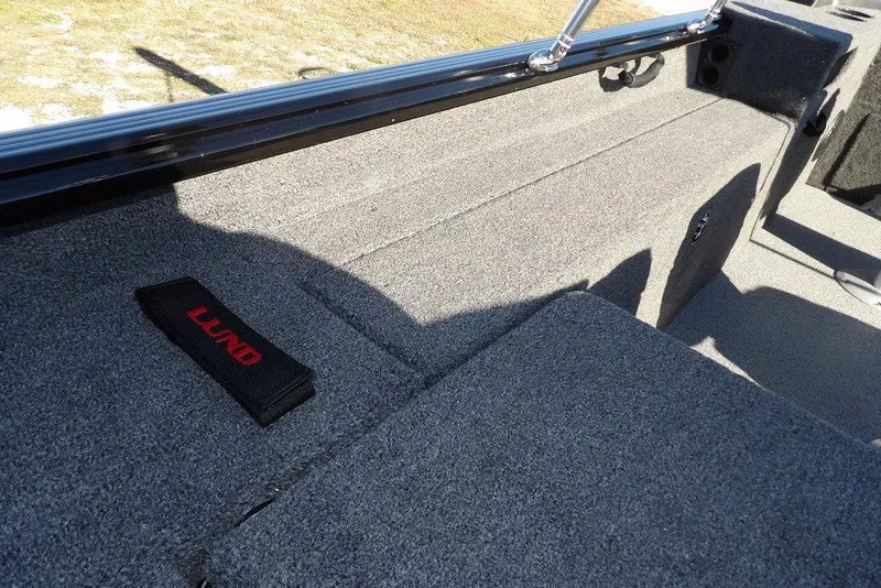 Slide: The Image of 2026 Lund 1875 Impact XS Sport boat interior with gray carpet and branded strap. - 15