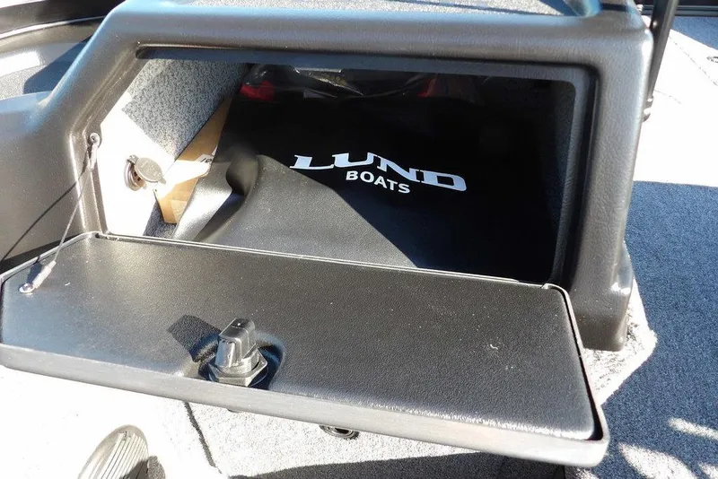 Slide: The Image of 2026 Lund 1875 Impact XS Sport boat storage compartment with logo visible. - 19