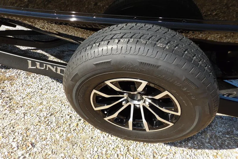 Slide: The Image of 2026 Lund 1875 Impact XS Sport trailer wheel on gravel surface. - 46