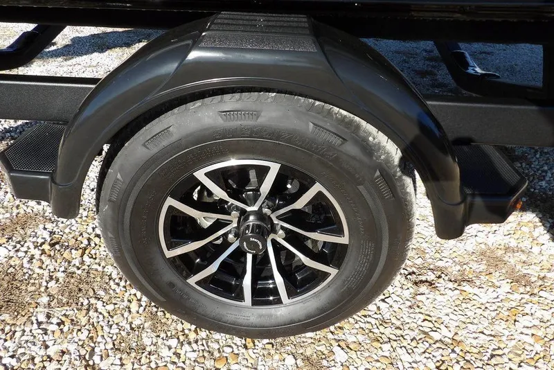 Slide: The Image of 2026 Lund 1875 Impact XS Sport trailer wheel on gravel surface. - 47