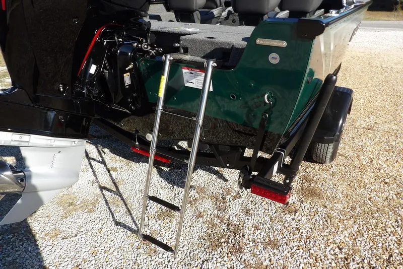 Slide: The Image of 2026 Lund 1875 Impact XS Sport boat with ladder and motor, parked on gravel. - 48