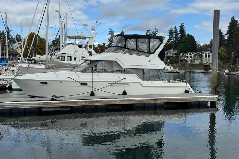 The Image of 1996 Carver 370 Voyager yacht docked in a marina, surrounded by calm water and other boats. - 0