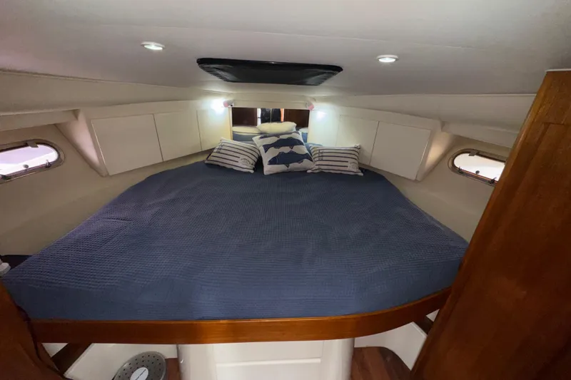 Slide: The Image of 1996 Carver 370 Voyager cabin with cozy bed, blue bedding, and nautical-themed pillows. - 23
