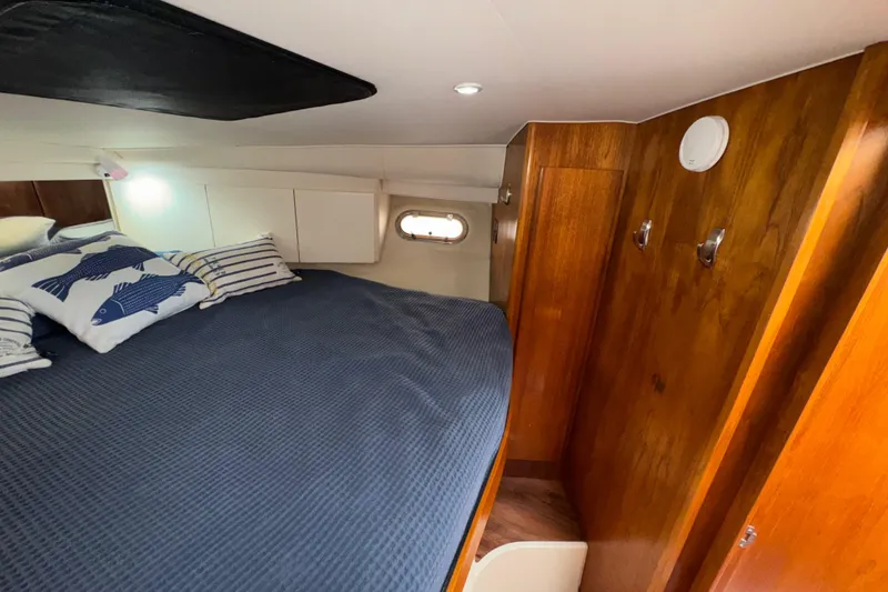 Slide: The Image of Cozy cabin interior of 1996 Carver 370 Voyager with bed, pillows, and wooden cabinetry. - 25
