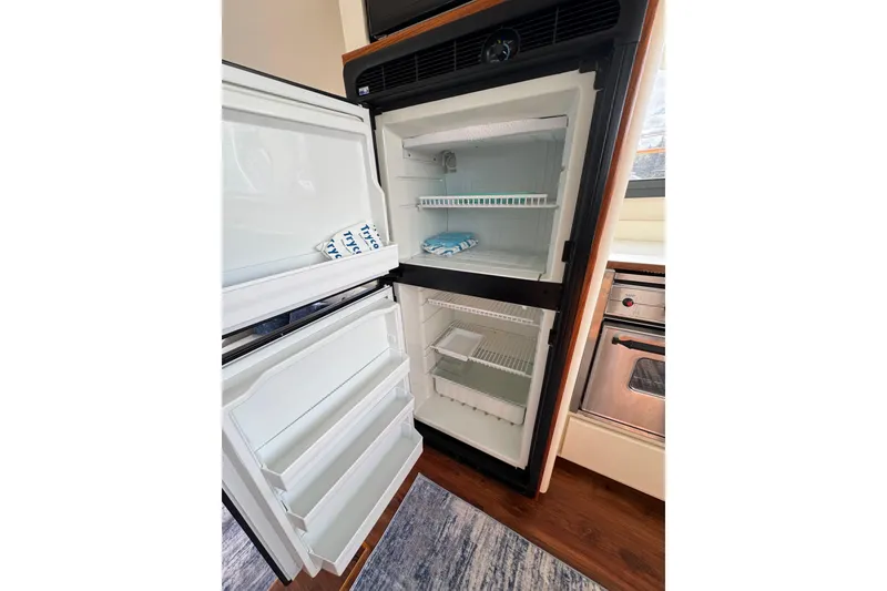 Slide: The Image of Open refrigerator inside 1996 Carver 370 Voyager yacht, showcasing spacious interior and shelves. - 47