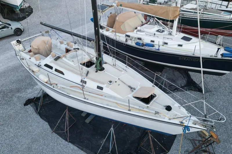 Slide: The Image of 1981 Ericson 36 sailboat on stands, aerial view, with covered cockpit and nearby parked car. - 7