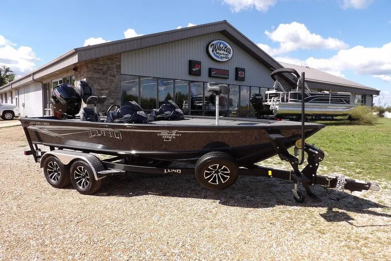 The Image of 2026 Lund 1875 Pro-V Bass XS boat on trailer outside marine center. - 1