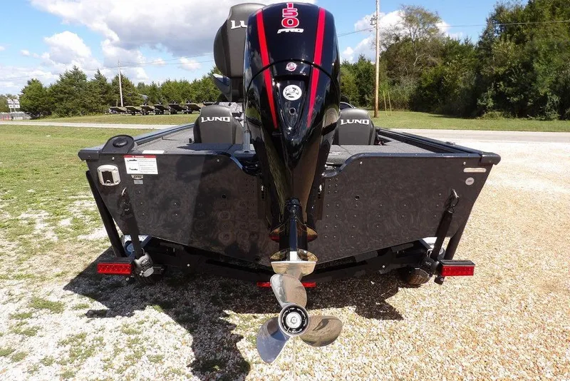 Slide: The Image of 2026 Lund 1875 Pro-V Bass XS boat with powerful outboard motor, parked on gravel. - 10