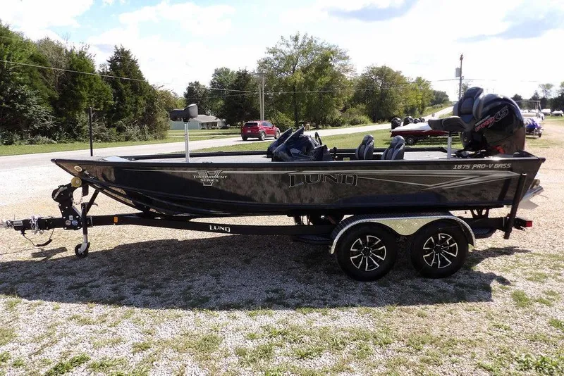 Slide: The Image of 2026 Lund 1875 Pro-V Bass XS boat on trailer, parked outdoors. - 2