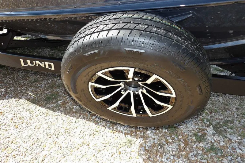 Slide: The Image of 2026 Lund 1875 Pro-V Bass XS trailer wheel on gravel surface. - 48