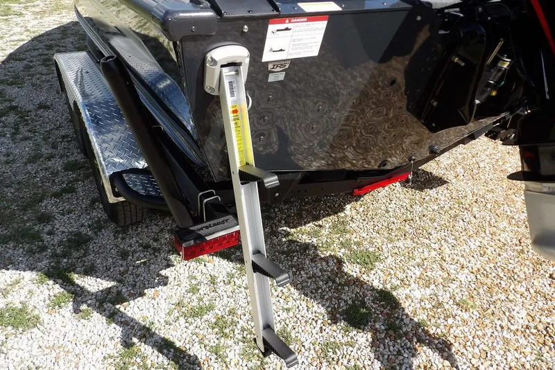 Slide: The Image of 2026 Lund 1875 Pro-V Bass XS boat trailer with ladder on gravel surface. - 56