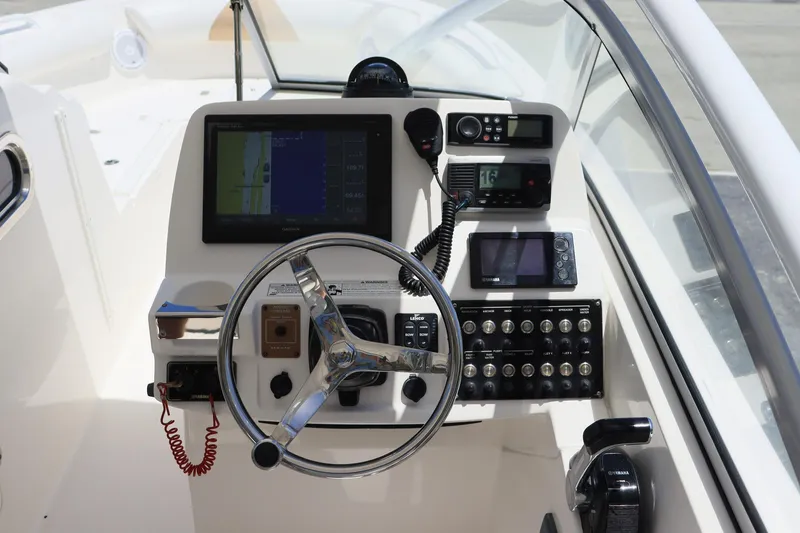 Slide: The Image of Control panel of a 2015 Everglades 245 CX boat with steering wheel and navigation equipment. - 12