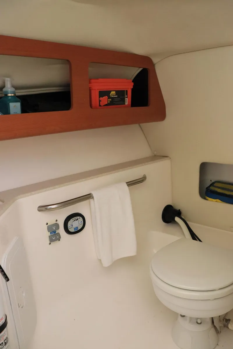 Slide: The Image of Interior of 2015 Everglades 245 CX boat featuring a compact marine toilet and storage shelves. - 14