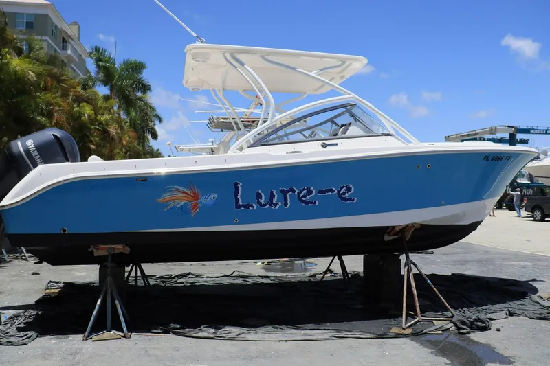 Slide: The Image of 2015 Everglades 245 CX boat named "Lure-e" on stands, blue and white design. - 3