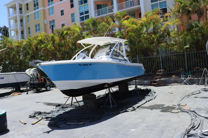 Slide: The Image of 2015 Everglades 245 CX boat on stands, blue hull, urban background. - 4