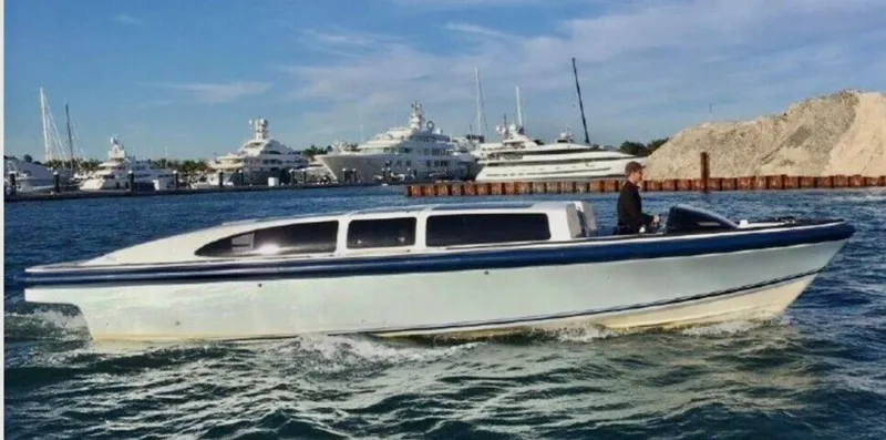 Slide: The Image of 2008 Goetz Custom Boats 33' Limo Tender cruising in a marina with yachts in the background. - 21