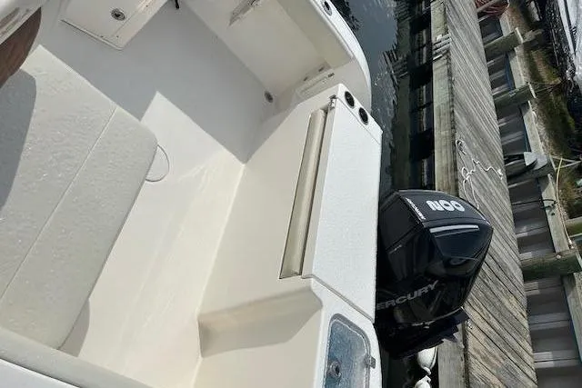 Slide: The Image of 2023 Cobia 220 DC boat interior with Mercury engine at dock. - 4