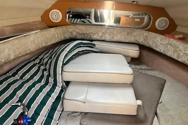 Slide: The Image of 2001 Regal 2550 LSC cabin interior with striped bedding and cushioned seating. - 4