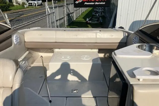 Slide: The Image of 2001 Regal 2550 LSC boat interior with seating and sink, parked near a fence. - 5