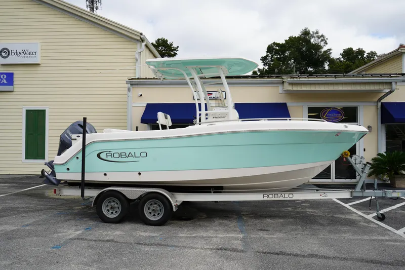 The Image of 2023 Robalo R222 Center Console boat on trailer, parked outside a building. - 0