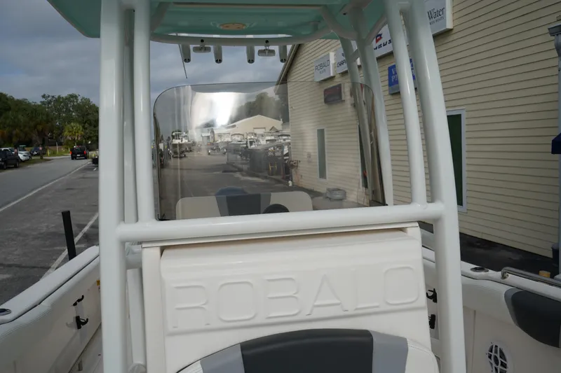 Slide: The Image of 2023 Robalo R222 Center Console boat, docked near a building, showcasing its helm area. - 19