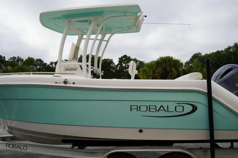 Slide: The Image of 2023 Robalo R222 Center Console boat on trailer, side view, teal and white design. - 4