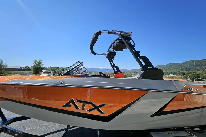 Slide: The Image of 2026 ATX Surf Boats 22 Type-S, orange and gray, with wakeboard tower, outdoors. - 12