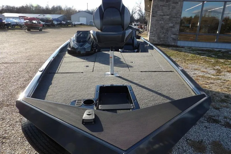 Slide: The Image of 2026 Lund 1875 Renegade boat, spacious deck, parked outdoors near a building. - 2