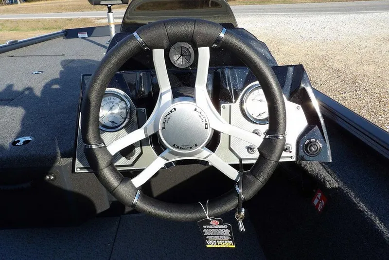 Slide: The Image of Steering wheel and dashboard of 2026 Lund 1875 Renegade boat, featuring gauges and controls. - 24
